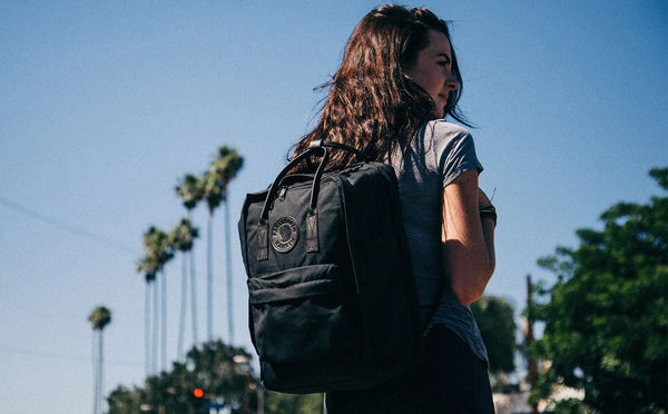 Person standing outdoors wearing a Fjällräven Kånken No. 2 backpack in black.