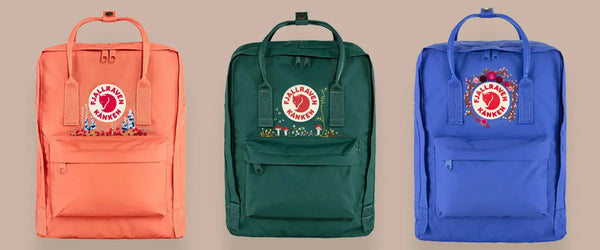 Trio of Custom Embroidery Fjällräven Kånken backpacks in coral, forest green, and royal blue on a neutral background.