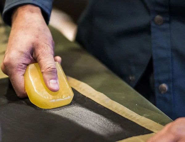 Hand applying Fjällräven Greenland Wax to a fabric for weatherproofing