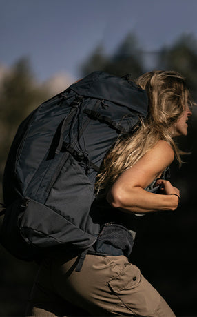 Woman carrying a Fjällräven backpack, showcasing durable design and ample storage for outdoor adventures and hiking trips.