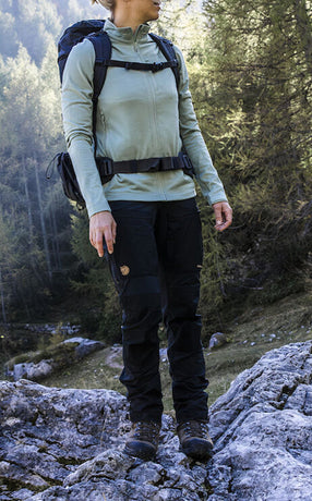 Woman wearing Fjällräven women's trousers on a rocky trail, showcasing durable and functional outdoor gear for hiking adventures.