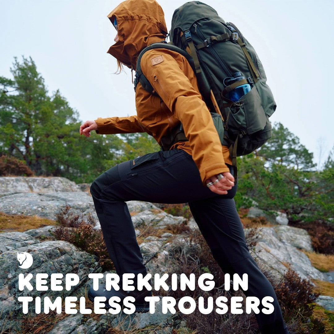 Person hiking on a rocky trail wearing Fjallraven trousers. Overlayed text 'Keep Trekking in Timeless Trousers'.